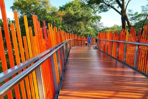 A wooden bridge with orange fence and a man walking across it. A wooden bridge with orange fence and a man walking across it.